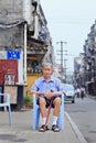 Elderley Chinese man sits on a plastic chair outside, Xiang Yang, China